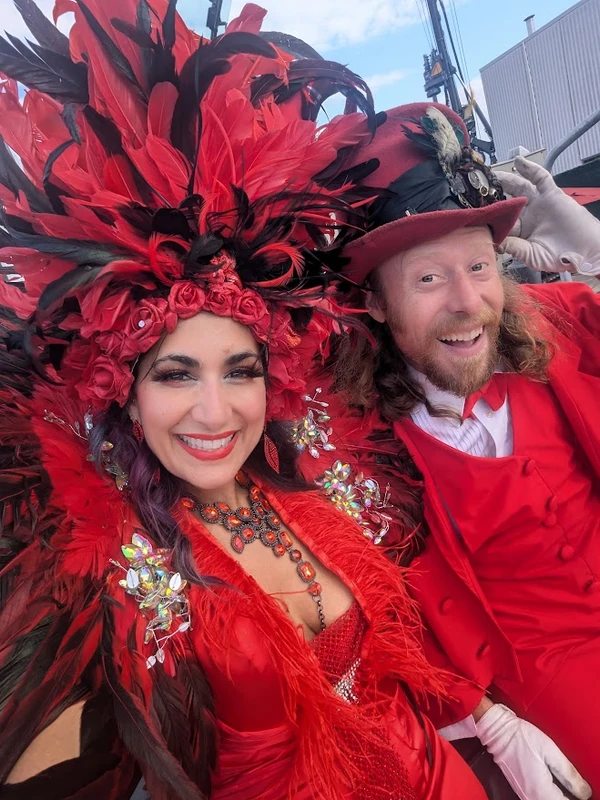 Red phoenix feathered stilt performer and ringmaster at outdoor event